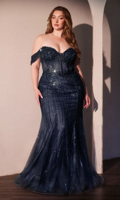 A woman in the Plus-size Blue Beaded Prom Gown: Ladivine CC341C, featuring an off-the-shoulder design and shimmering sequins, stands indoors against a light-colored wall.