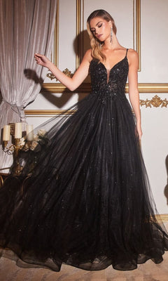 A woman in the Sheer-Corset Long Prom Ball Gown CD0154 in black, featuring a beaded plunging bodice, thin straps, and a full glitter-tulle skirt, poses in an ornate room with gold-trimmed walls.