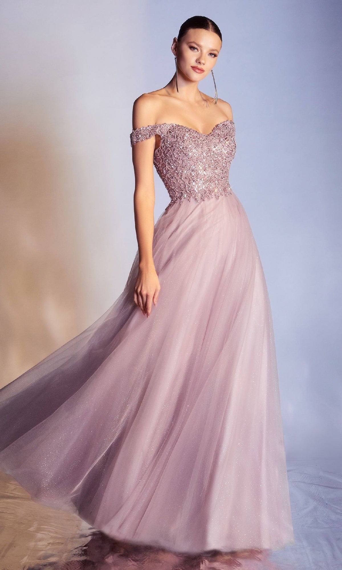 A woman models the Beaded-Bodice Long Prom Dress: Ladivine CD0177, featuring an off-the-shoulder light purple sequined bodice and flowing tulle skirt, posed elegantly against a soft gradient background.