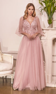 A woman stands indoors by a white fireplace and chair, wearing the affordable Ladivine CD0182 Sheer-Sleeve Long Prom Dress—a light pink gown with floral details.