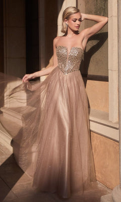 A woman stands outdoors in sunlight, wearing the Lace-Up Strapless Long Glitter Prom Dress CD0217 with a gold-sequined bodice and sheer tulle skirt, elegantly holding out part of the skirt to the side.