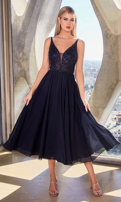 A woman stands indoors by a window with city buildings behind her, wearing the Sheer-Bodice Tea-Length A-Line Party Dress CD0225 in black, featuring a sleeveless design and an embellished sheer bodice.