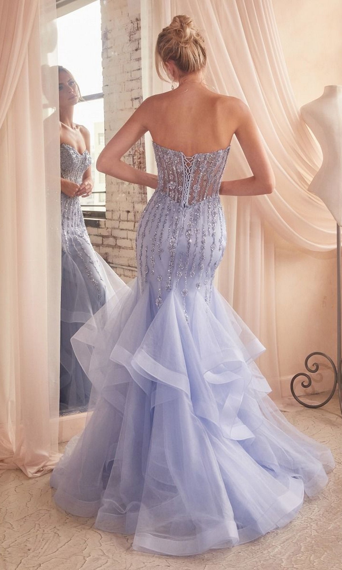 A woman wearing the Strapless Sweetheart Long Mermaid Prom Dress CD332 with bead embellishments stands before a mirror in a softly lit room, highlighting the elegance of this lavender evening gown.