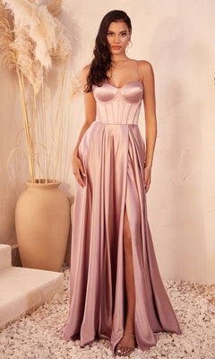 A woman stands indoors on white stones next to a large beige vase of pampas grass, wearing the Ladivine CD337 Long Sweetheart A-Line Prom Dress in blush pink with thin straps and a thigh-high slit.