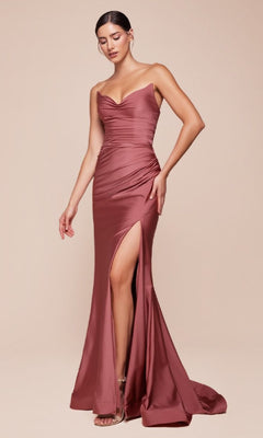 A woman wears the Ladivine CD791 Lace-Up Strapless Long Prom Dress, featuring a rose satin finish, open lace-up back, draped bodice, thigh-high slit, and floor-length skirt, standing against a plain beige background.