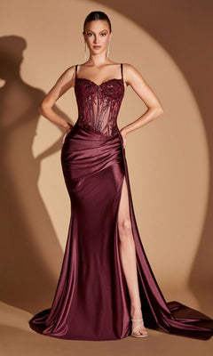 A woman in the Sheer-Corset Long Sweetheart Prom Dress CD868 in plum noir, featuring a sheer beaded lace corset bodice, spaghetti straps, a ruched satin skirt with a train, and a thigh-high slit, poses against a warm beige backdrop.