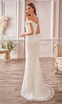 A woman stands in an elegant room wearing the Ladivine CD929, a long off-white wedding dress with an off-the-shoulder design and a small train, looking over her shoulder.