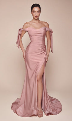 A woman poses in the Plus-Size Long Prom Dress with Bows CD943C, featuring blush pink fabric, draped details, bow-adorned sleeves, and a thigh-high slit, set against a plain beige background.