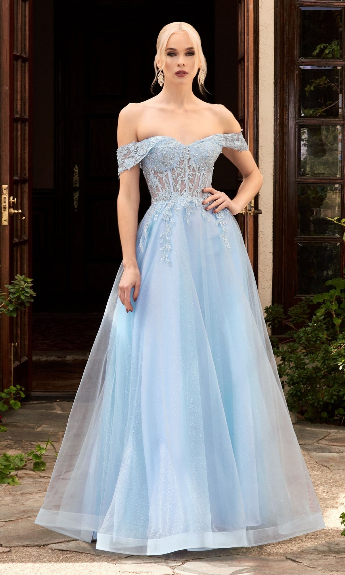 A woman in the Sheer-Bodice Long Glitter Prom Ball Gown CD961 stands in front of open wooden doors.