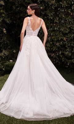 A woman in the Ladivine CDS511W long wedding dress with a lace-embroidered bodice and flowing tulle skirt stands outdoors amid green foliage.