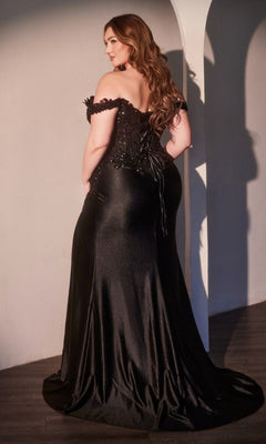 A woman with long wavy hair wears the Ladivine CDS537C Plus-Size Off-Shoulder Prom Gown with a lace-up back, standing in a room with white walls and wooden floors.
