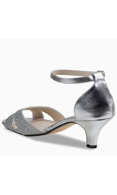 The Clementine Silver Glitter Prom Shoes (Touch Ups 4613) are kitten heels with an ankle strap, closed heel, and open toe, shown angled from the back.