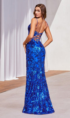 A woman wears the Ladivine CM350 Lace-Up Long Sequin Formal Dress, a sleeveless, floor-length gown with blue sequins and an open lace-up back, standing indoors before white curtains.