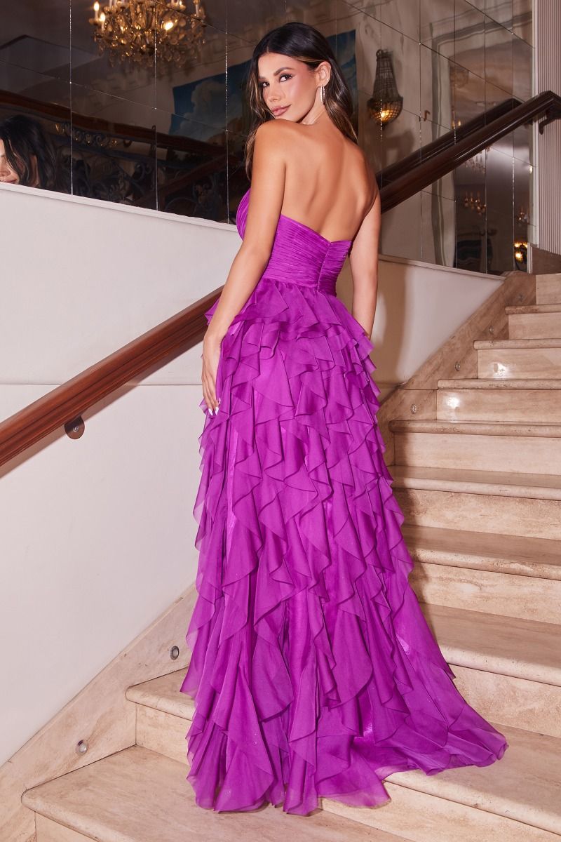 A woman wearing the Ladivine CZ0027 Strapless Long Ruffle Prom Dress stands on a staircase, looking over her shoulder.