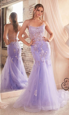 A woman stands in front of a mirror wearing the Long Pastel Floral Mermaid Prom Dress D145, a fitted lavender gown with appliqués, a sheer bodice, thin straps, and an open-back formal mermaid design.