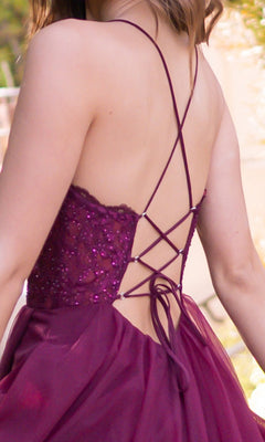 A person wearing the Velvi Long Sweetheart A-Line Prom Dress Dani, a sleeveless maroon gown featuring a sequined bodice, crisscross lace-up straps, and a backless design.