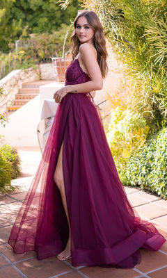 A woman stands on a tiled patio surrounded by greenery, wearing the Velvi Long Sweetheart A-Line Prom Dress Dani, a sleeveless, floor-length formal dress with a high slit.