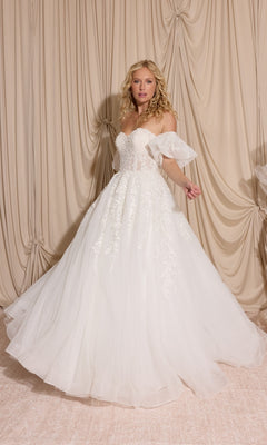 Woman in the Long Wedding Dress: Eureka EK155 in off white with lace details and detachable puff sleeves stands before beige curtains, holding out her elegant gown.