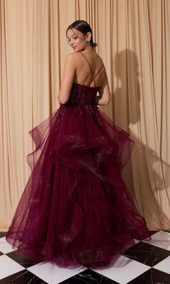 A woman wearing the Long Prom Dress: Eureka EK167, featuring a burgundy layered tulle A-line skirt and spaghetti straps, stands on a black-and-white tiled floor before beige curtains, smiling as she faces slightly away.