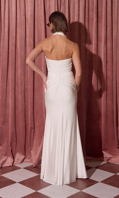 A woman wearing the Eureka EK191 long prom dress stands with her back to the camera before pink curtains on a checkered floor.