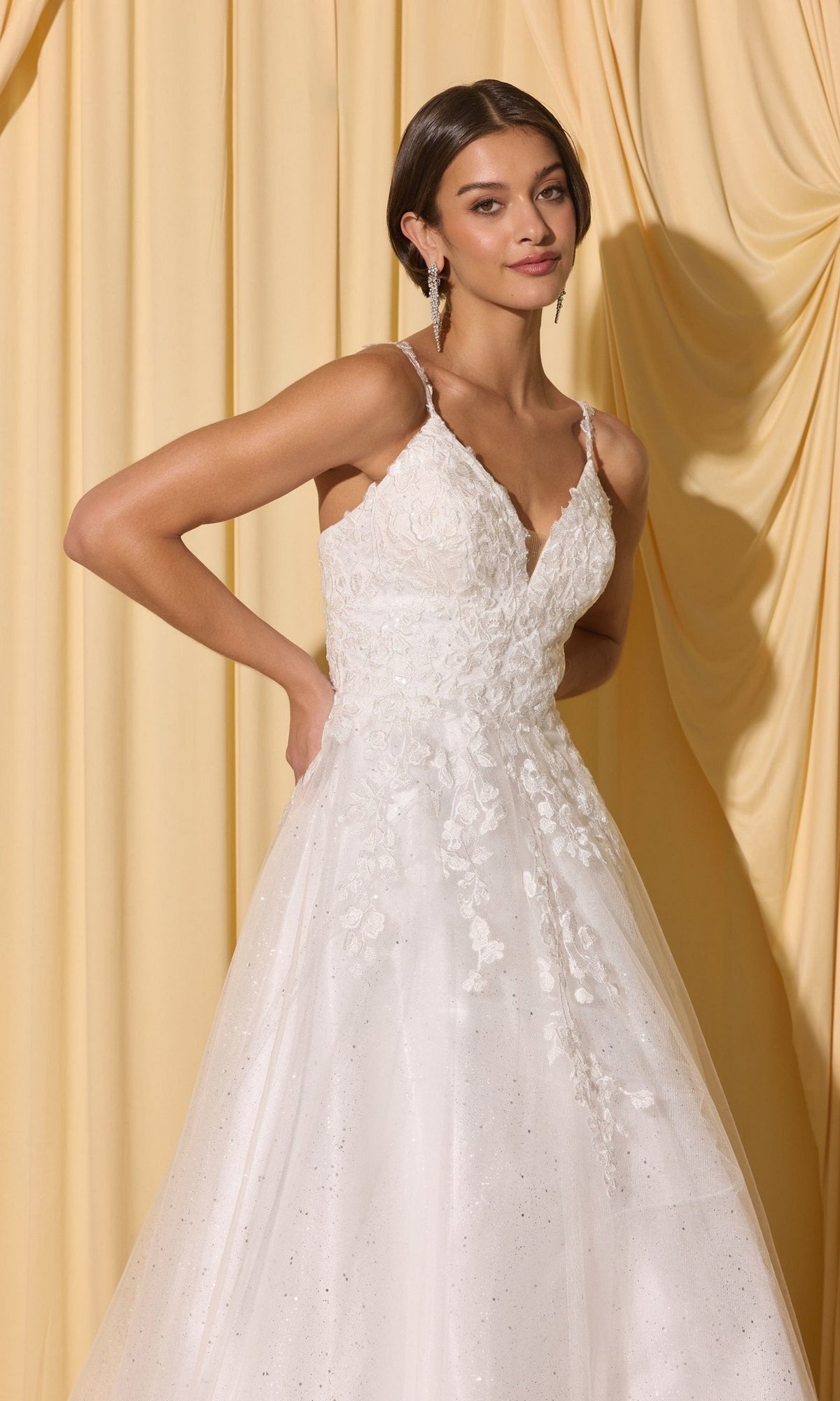 Woman poses with one hand on her hip in front of light yellow draped curtains, wearing the Long Prom Dress: Eureka EK210—sleeveless, white lace with 3D floral appliques.
