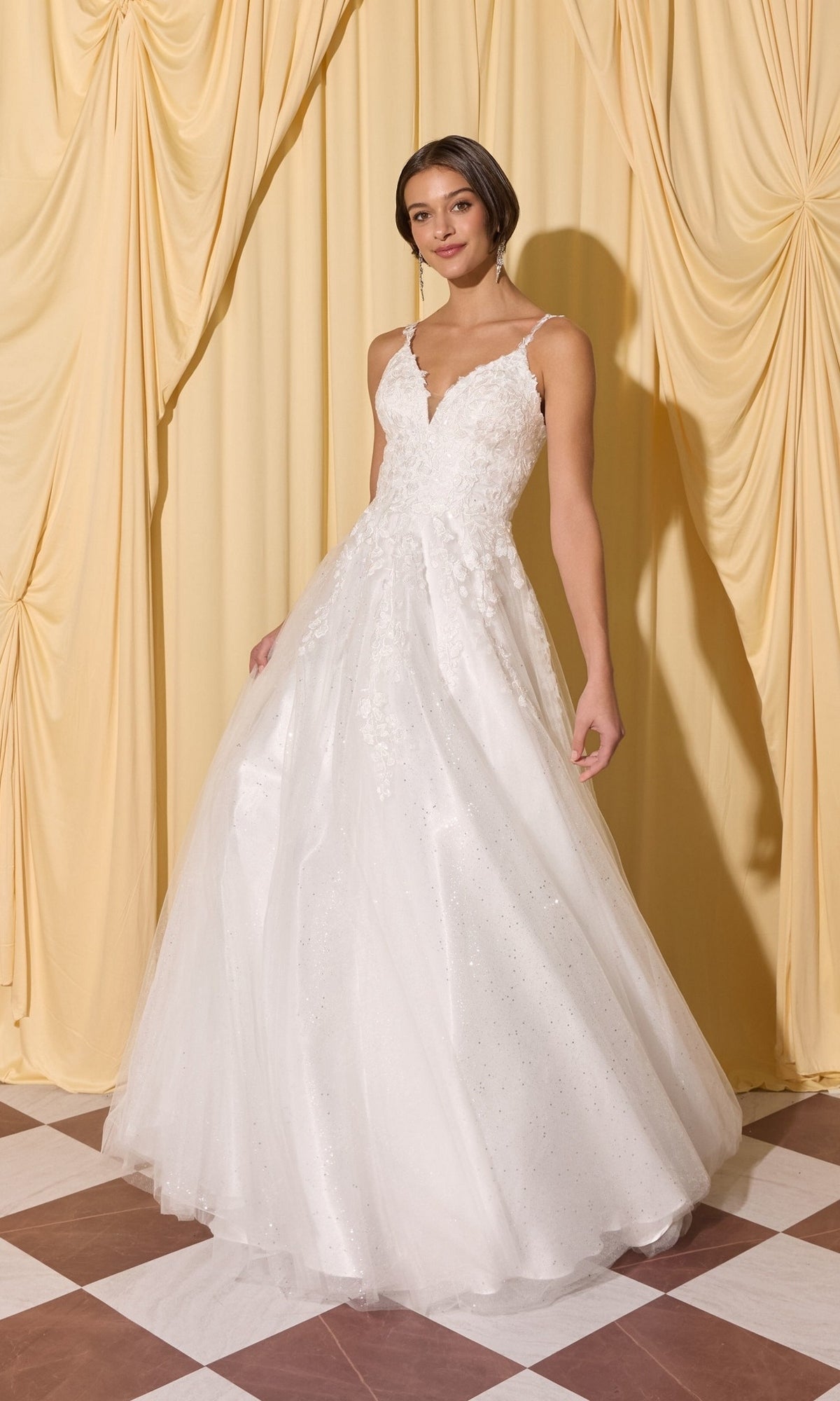 Woman in Long Prom Dress: Eureka EK210, a white sleeveless floor-length gown with 3D floral appliques, stands on a checkered floor before yellow draped curtains.