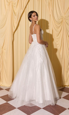 Woman in a white Long Prom Dress: Eureka EK210 with 3D floral appliques stands on a checkered floor, facing away, with yellow curtains behind her.