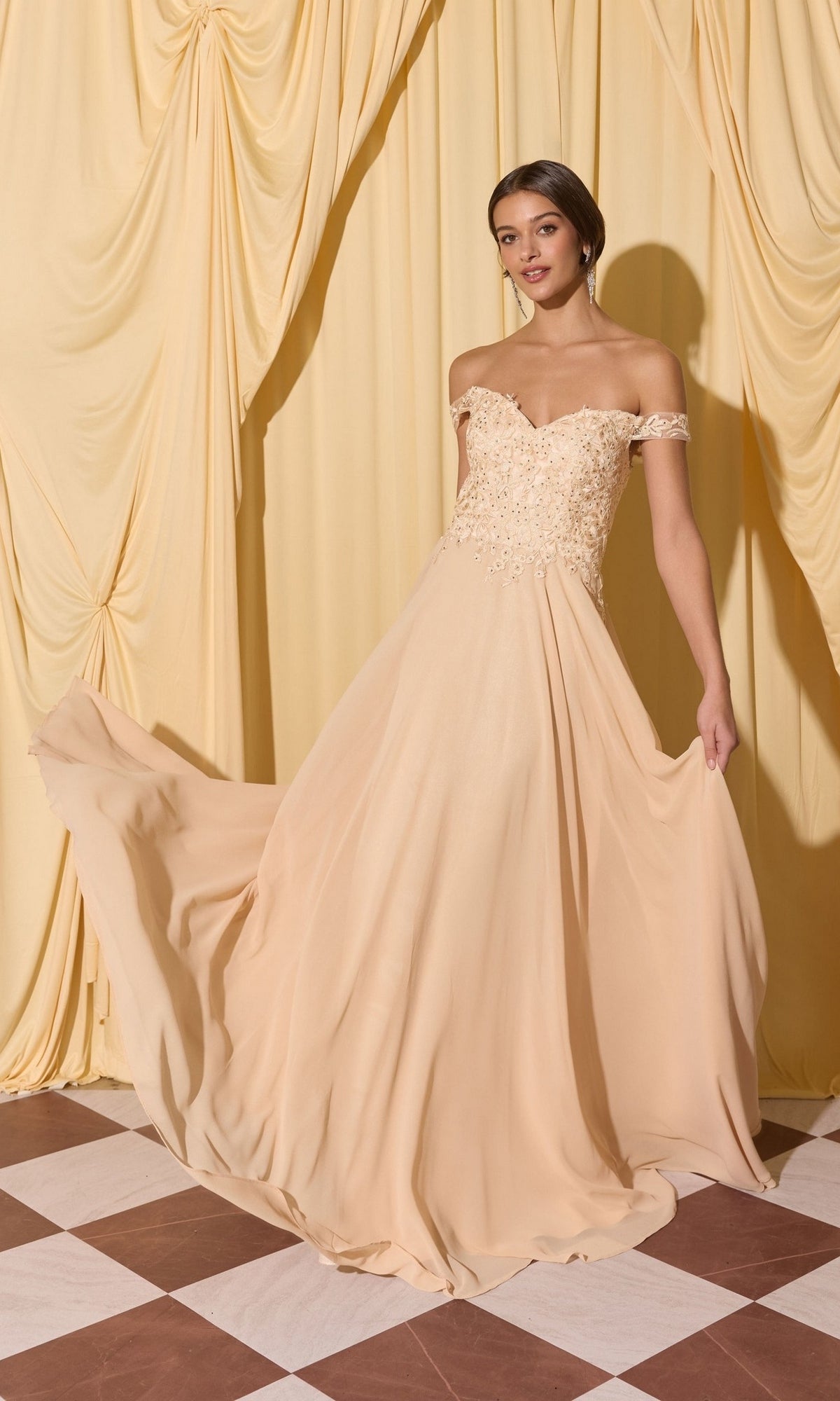 Woman in the Long Prom Dress: Eureka EK211—a floor-length light peach off-shoulder gown with lace applique, holding her skirt on a checkered floor before yellow curtains.