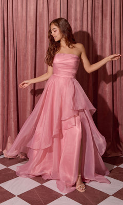 A woman in a Dusty Rose Long Prom Dress: Eureka EK216 with an a-line skirt stands on a checkered floor, pink curtains behind her, gazing to the side.