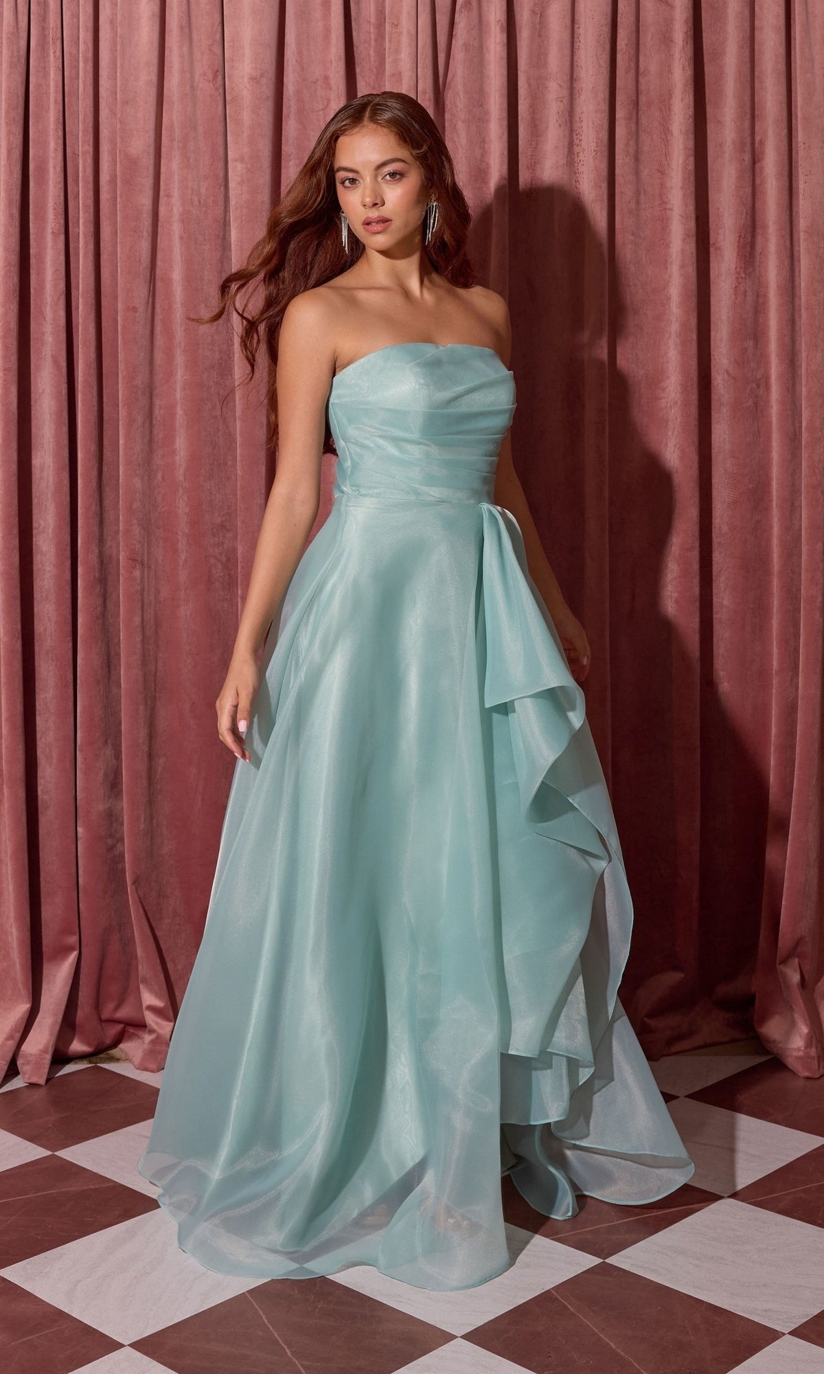 Woman wearing the Long Prom Dress: Eureka EK216, a strapless light blue gown with a layered A-line skirt, on a checkered floor before pink curtains.