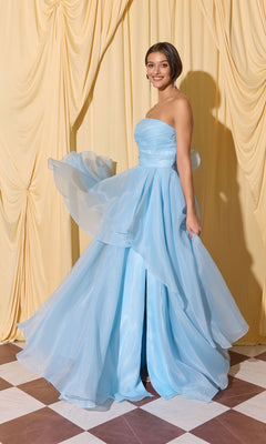 Smiling at the camera, a woman in the Long Prom Dress: Eureka EK216 in powder blue stands on a checkered floor before gathered cream curtains.