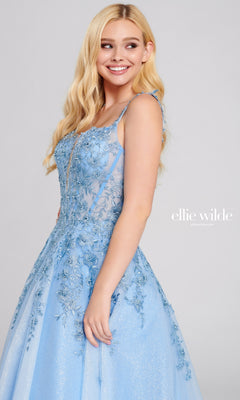 A woman with long blonde hair models the Ellie Wilde EW120014 Long Glitter Prom Ball Gown in light blue, featuring tulle and floral embroidery, against a plain background. The text "ellie wilde" appears beside her.