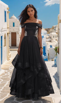 A woman in the La Femme Off-Shoulder Long Tiered Prom Dress 27224 stands on a stone path between white buildings with blue accents under a clear Mediterranean sky.