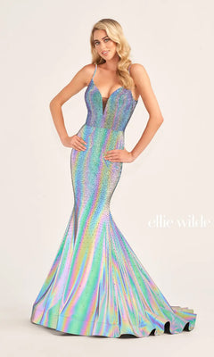 A woman models the Ellie Wilde Supernova Mermaid Prom Dress EW35701, featuring a deep V-neckline, thin straps, iridescent fabric, and sparkling accents. The "ellie wilde" logo is displayed against a plain background.