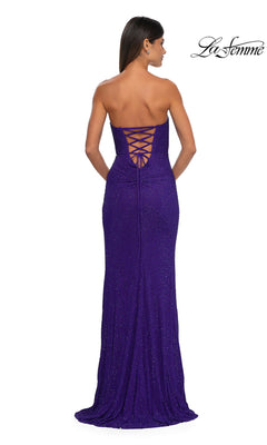 A woman stands facing away, wearing the La Femme 32422 Strapless Long Glitter Prom Dress—a floor-length purple gown with a sweetheart neckline and lace-up back.