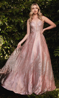 A woman in a Rose Gold Long Glitter-Print Prom Ball Gown J819 stands outdoors in front of leafy green foliage.