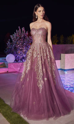 A woman in the Strapless Sweetheart Long Prom Ball Gown J852 with gold embroidery stands outdoors by a pool at night, her floor-length purple dress resembling an elegant evening gown.
