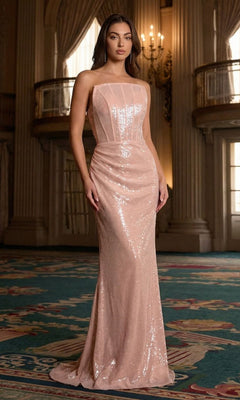 A woman stands in an elegant room wearing the Ladivine J904 pink prom dress—a strapless, fitted, floor-length gown with a structured bodice and sparkling sequins—ideal for those seeking a timeless and glamorous look.