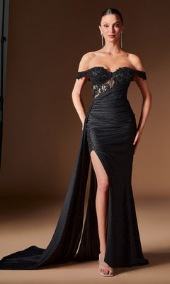 A woman stands against a plain brown background wearing the Ladivine J914—a long black prom dress with an off-the-shoulder sweetheart neckline, sheer corset bodice, high slit, floor-length train, and metallic heels.
