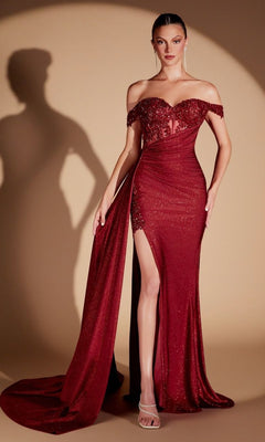A woman stands against a beige background wearing the Ladivine J914, a burgundy long prom dress featuring an off-the-shoulder, form-fitting silhouette with a thigh-high slit, sweeping train, glittery fabric, elegant sweetheart neckline, and a sequin embroidered corset bodice.