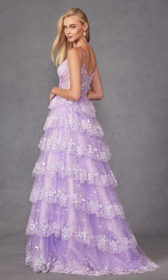 A woman in the Juliet JT2454K Long Ruffled A-Line Prom Ball Gown stands against a gray studio backdrop, looking over her shoulder in this elegant lavender, tiered lace dress with floral embroidery.
