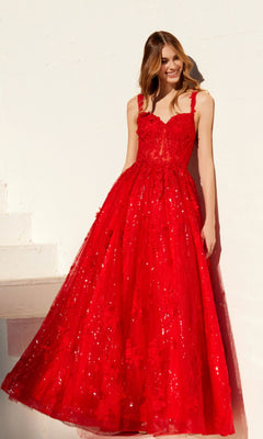 A woman stands against a white wall wearing the Juliet JT2495A, a floor-length, sleeveless red sequin-lace prom dress.