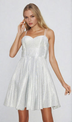 A woman stands against a plain light background wearing the Lace-Up Short Glitter A-Line Homecoming Dress 8011J, a sleeveless silver semi-formal dress with thin double straps and a sparkly shimmery finish for an elegant look.