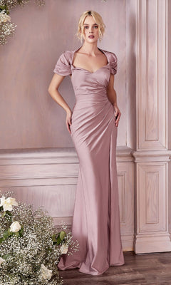 A woman stands indoors surrounded by light wood paneling and floral arrangements, wearing the CLKV1061 Cap-Sleeve Long Satin Prom Dress—a floor-length, fitted mauve gown featuring cap sleeves and a sweetheart neckline.
