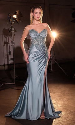 A woman wears the Strapless Long Prom Dress: Ladivine KV1132, a light blue satin gown with a beaded corset bodice, intricate detailing, and high leg slit, posing in front of studio lights.