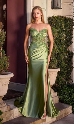 A woman stands outside near greenery in the Ladivine KV1132 strapless long prom dress, featuring light green satin, a thigh-high slit, and lace detailing.