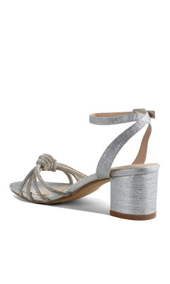 The Libra Silver Glitter Prom Shoes: Touch Ups 4651 are stylish block-heeled sandals with an ankle strap, open toe, and decorative knot—perfect comfortable silver prom shoes for those seeking chic block heel footwear.