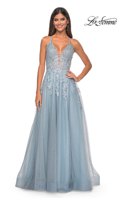 A woman wearing the La Femme Lace-Embroidered Long Prom Dress 32147 in light blue, featuring thin straps, a sheer bodice detail, floral lace appliqué, and a flowing tulle skirt.