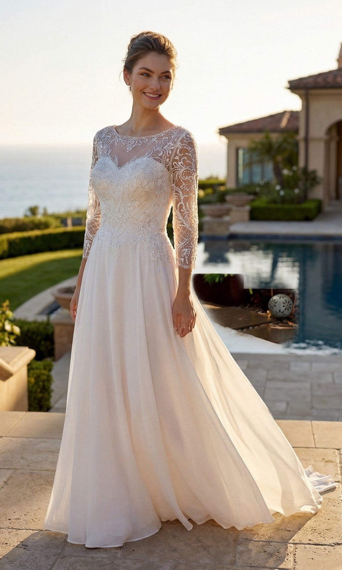 A woman wearing the Juliet M11-W long formal dress in off white, featuring an embroidered bodice and lace sleeves, stands outdoors by a poolside with a house and ocean in the background.
