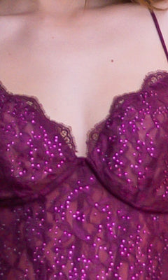 A close-up of a person wearing the Velvi Lace-Bodice Long Lace-Up Prom Dress Misha, featuring purple sequins, thin straps, and sheer-lace corset detailing.